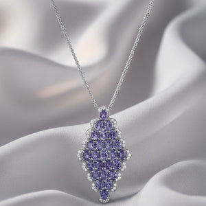 Purple gemstone pendant necklace on a soft fabric background 18K gold tanzanite diamond necklace flatlay – luxury fine jewelry by Tresor Collection