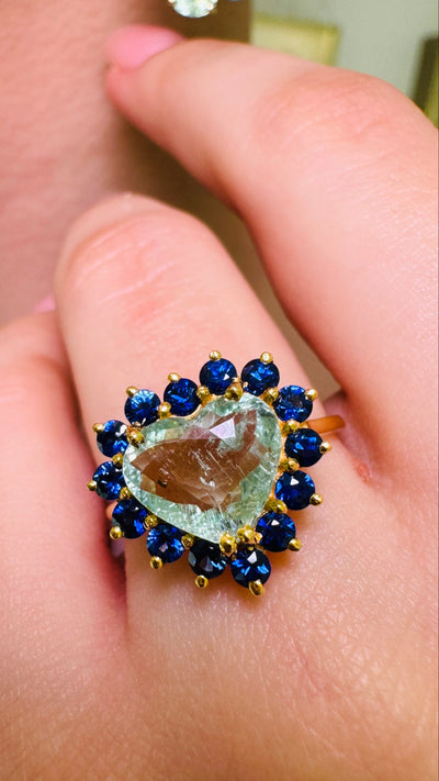 Paraiba Tourmaline Heart shape And Blue Sapphire Round Ring In 18K Yellow Gold - Tresor Collection Paraiba tourmaline heart ring with blue sapphire halo worn on hand – vibrant gemstone statement ring