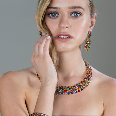 Woman wearing a colorful necklace and earrings against a gray background Handcrafted multicolor tourmaline statement necklace styled on model – luxury fine jewelry by Tresor Collection