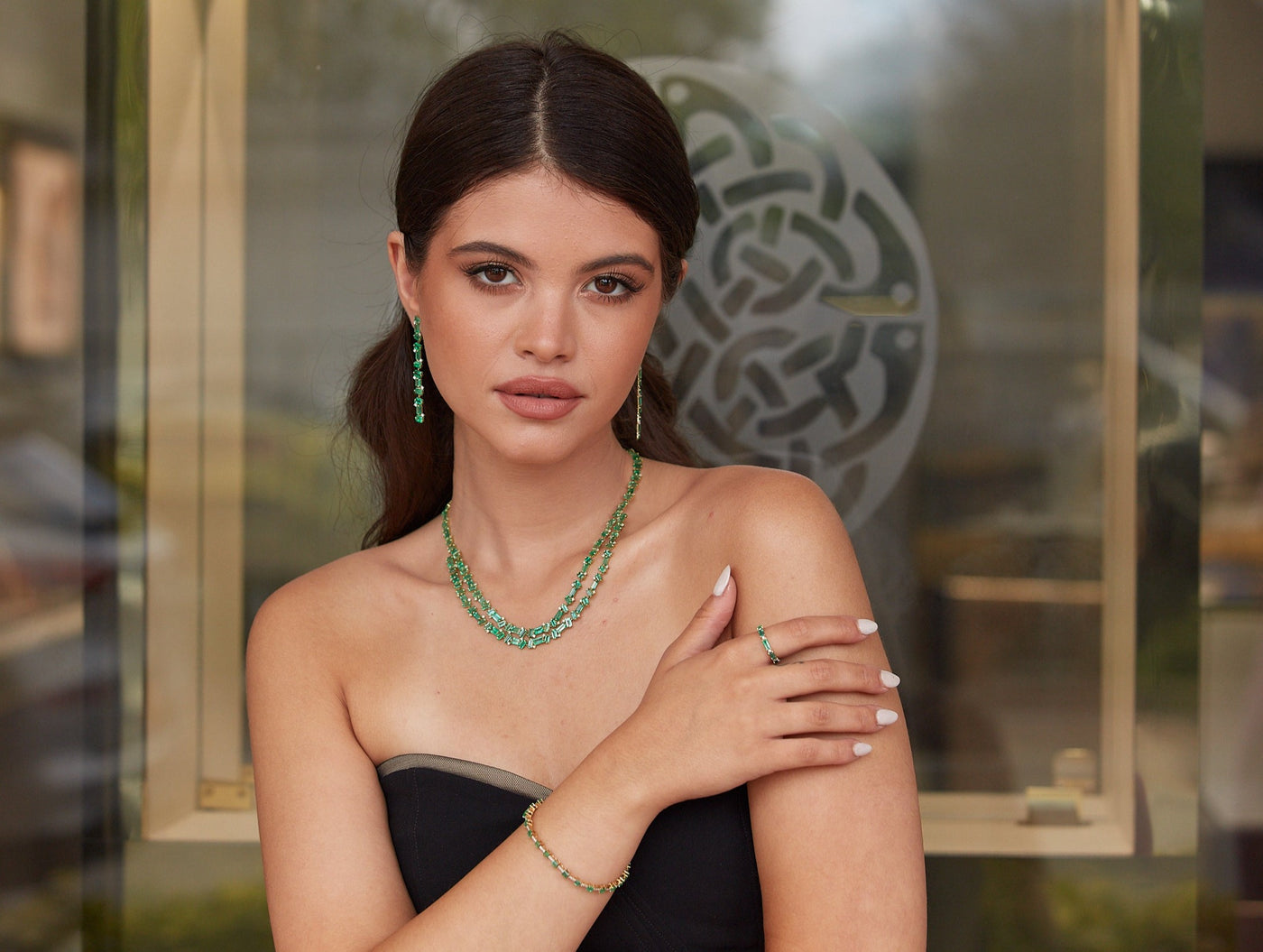 Model wearing double-strand emerald bead necklace with hand on shoulder – statement gemstone jewelry by Tresor Collection