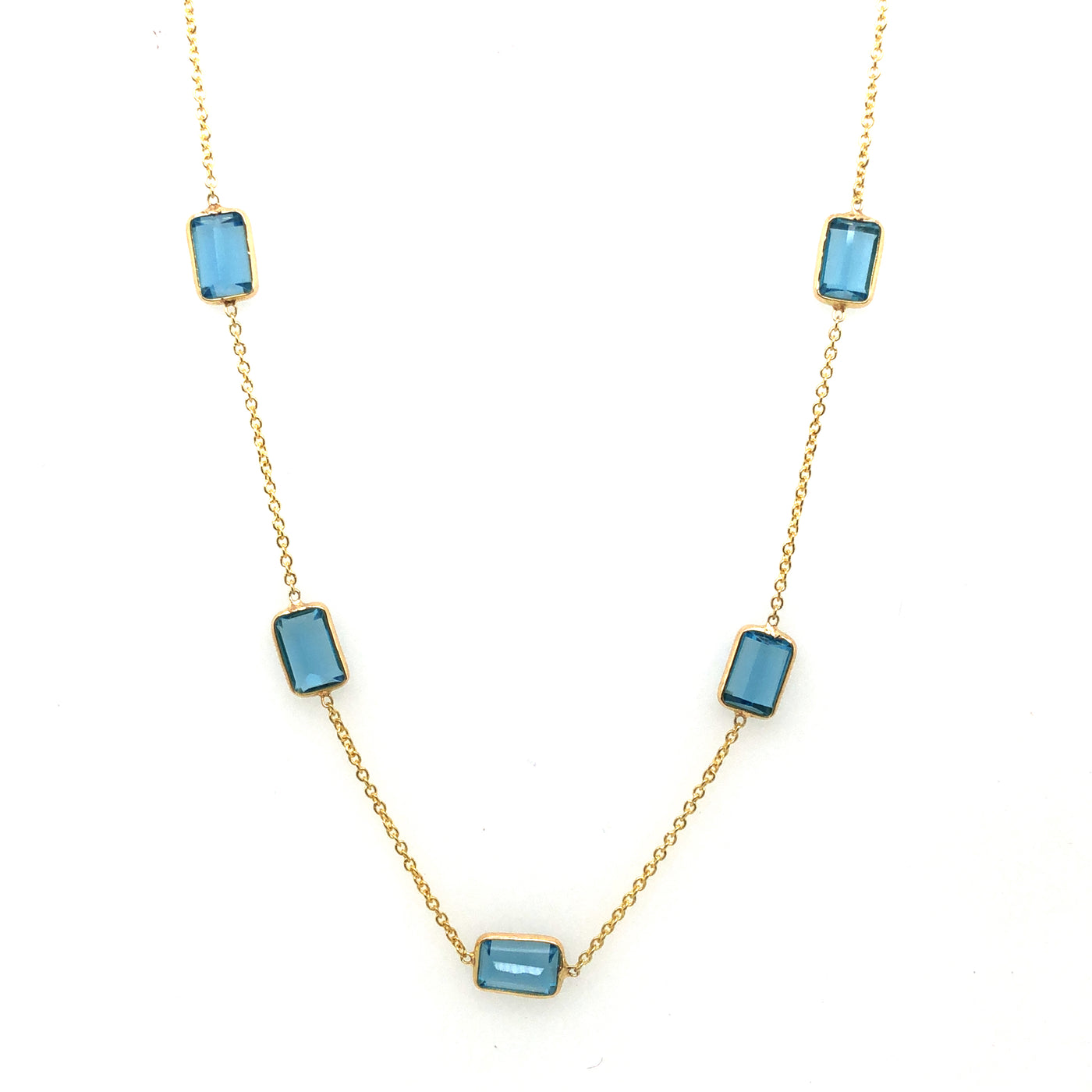 Necklace with blue gemstones on a white background Blue Topaz station necklace flatlay – elegant handcrafted fine jewelry by Tresor Collection