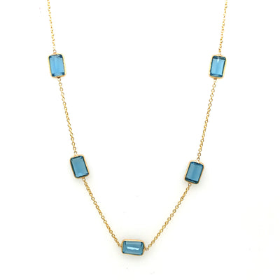 Necklace with blue gemstones on a white background Blue Topaz station necklace flatlay – elegant handcrafted fine jewelry by Tresor Collection