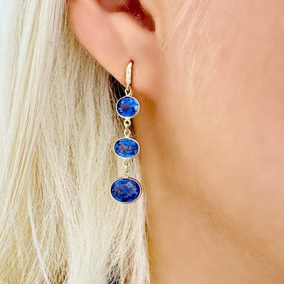Tanzanite Oval & Diamond Earring In 18K Yellow Gold - Tresor Collection  Model wearing 18K gold Tanzanite drop earrings – side view showcasing gemstone sparkle