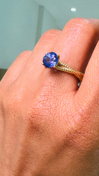 Tanzanite Round Ring In 18K Yellow Gold - Tresor Collection Close-up of tanzanite ring on finger – highlighting the gemstone’s color and elegance.