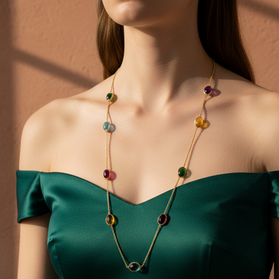 Woman wearing a green off-shoulder top with a colorful necklace against a neutral background Elegant multicolor gemstone necklace on model – designer gold jewelry for women by Tresor Collection