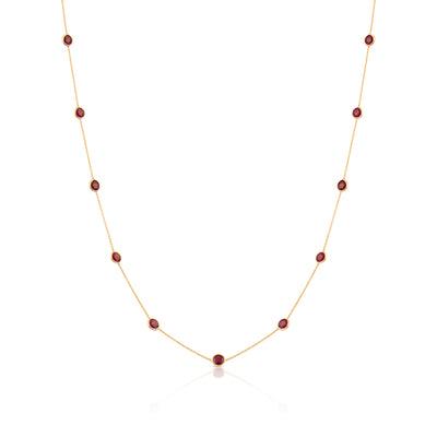 A round necklace made of 18k yellow gold with a series of red gemstones attached to it. 18K gold multi-gemstone necklace flatlay – luxury fine jewelry by Tresor Collection