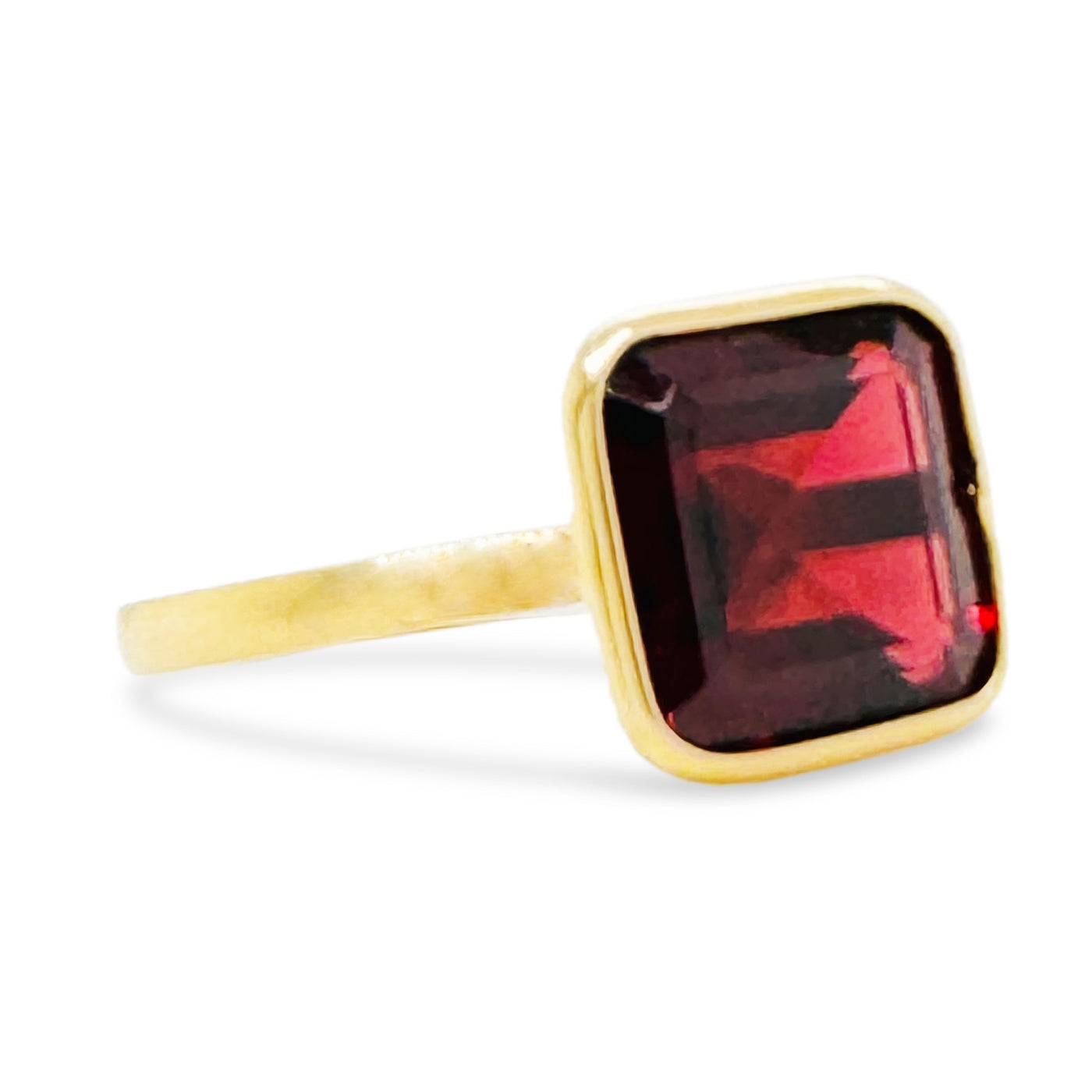 Gold ring with a red gemstone on a white background Side view of 18K gold square-cut rhodolite garnet ring – fine artisan jewelry by Tresor Collection