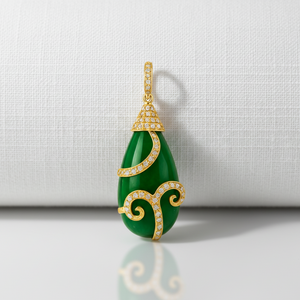 Green teardrop pendant with gold accents on a light gray background 18K gold emerald pendant flatlay – handcrafted fine jewelry by Tresor Collection