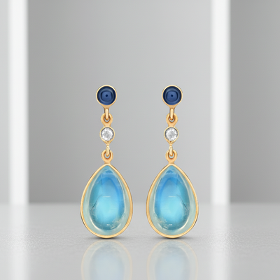 Teardrop-shaped earrings with blue stones and gold accents on a gray background Pair of Rainbow Moonstone and Blue Sapphire teardrop earrings – artisan-crafted gemstone jewelry in gold