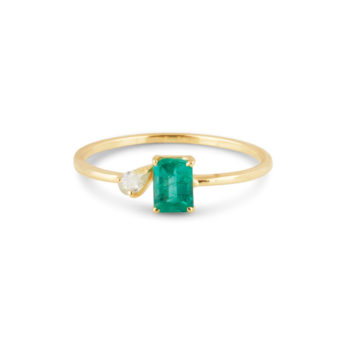 Emerald-cut emerald ring with pear-cut diamond accent in gold – minimalist fine-jewelry flatlay