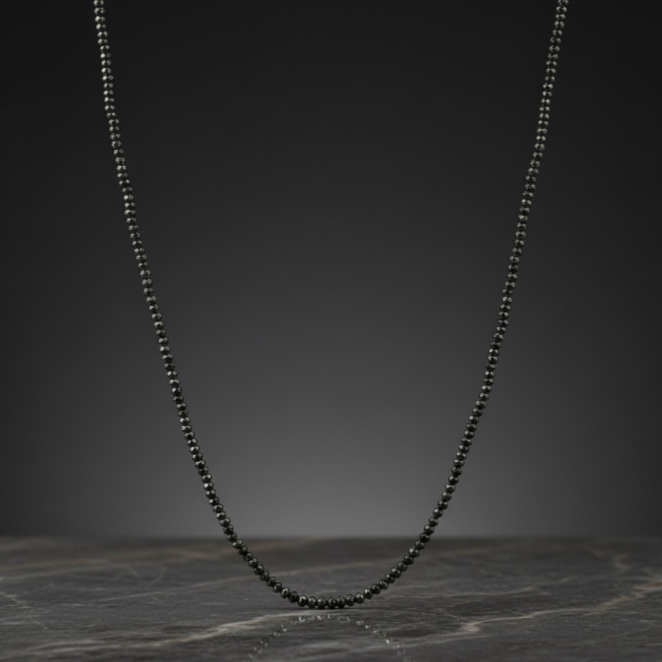 Black beaded necklace on a dark marble surface
