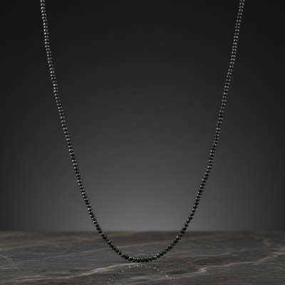 Black beaded necklace on a dark marble surface