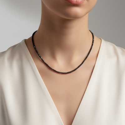 Black beaded necklace worn by a model against a neutral background