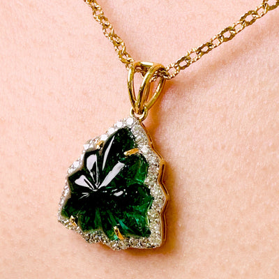 A close up view of tresor collection's carved emerald leaf cut pendant studded with diamonds in 18kt Yellow gold Emerald pendant styled for festive and bridal wear – luxury handcrafted jewelry from Tresor Collection