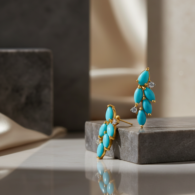 Turquoise earrings with gold accents on a reflective surface Close-up of 18K gold turquoise and diamond earrings – handcrafted fine jewelry from Tresor Collection boutique
