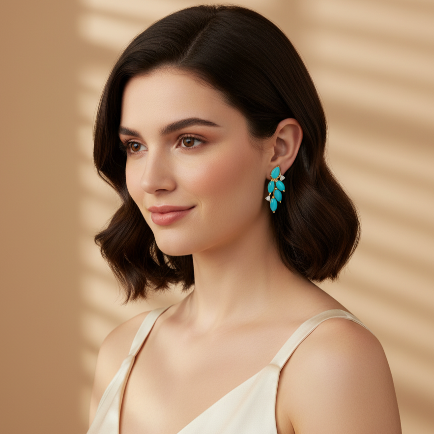 Woman wearing a white dress and turquoise earrings against a beige background Turquoise and diamond gold earrings styled for festive and bridal looks – luxury handcrafted jewelry from Tresor Collection
