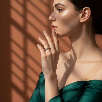 Woman in a green dress with a ring on her finger against a warm-toned wall. Elegant rainbow moonstone gold ring on model – designer fine jewelry for women by Tresor Collection