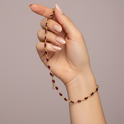 Hand holding a gold bracelet with red gemstones against a neutral background Elegant rhodolite necklace on model – designer gold jewelry for women by Tresor Collection