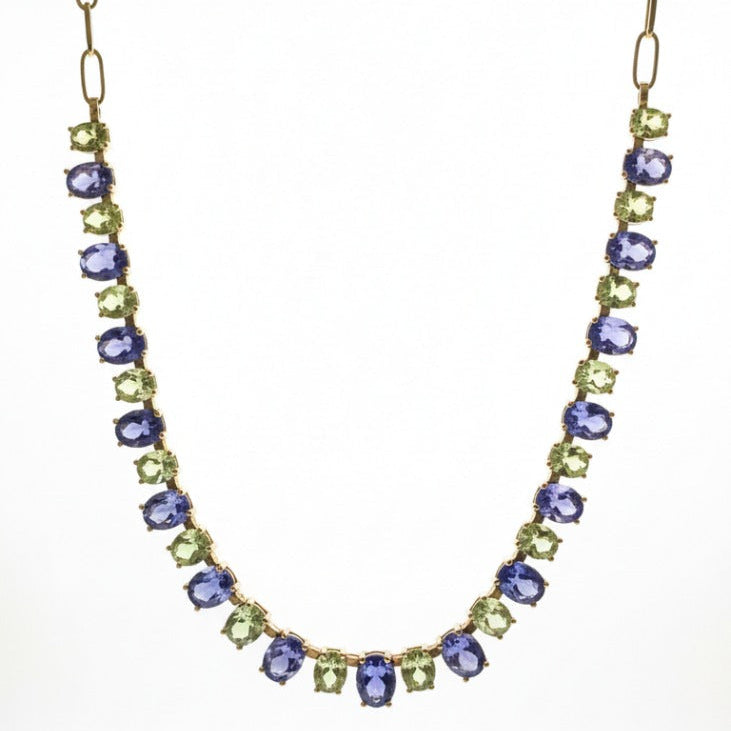 Necklace with purple and green gemstones on a white background 18K gold Tanzanite and Tsavorite necklace flatlay – luxury handcrafted fine jewelry by Tresor Collection
