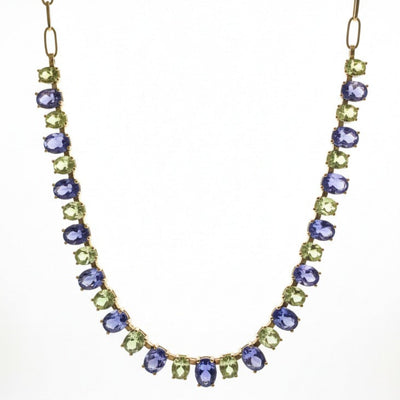 Necklace with purple and green gemstones on a white background 18K gold Tanzanite and Tsavorite necklace flatlay – luxury handcrafted fine jewelry by Tresor Collection