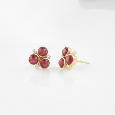 Pair of gold earrings with red gemstones on a white background 18K gold ruby and diamond floral earrings flatlay – luxury fine jewelry by Tresor Collection