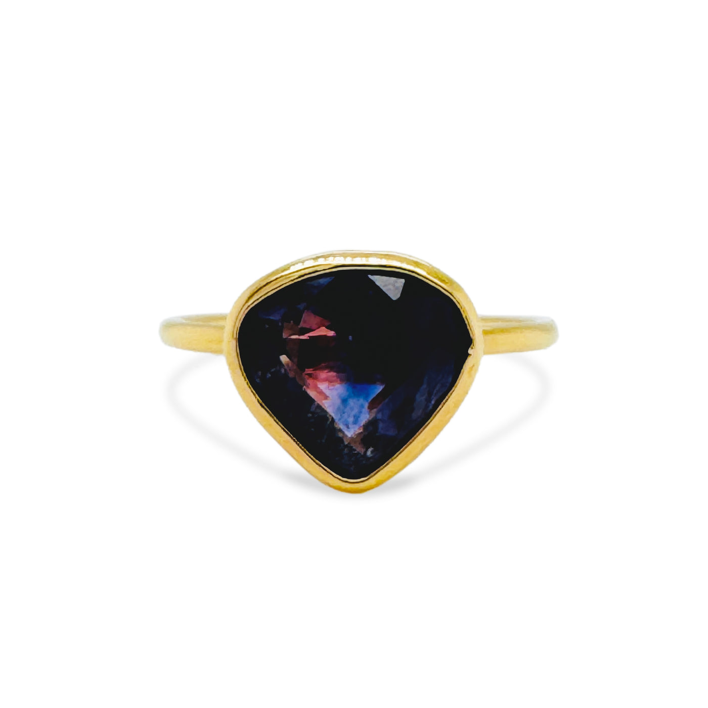 Gold ring with a dark stone featuring colorful nebula design on a white background 18K gold blue sapphire ring flatlay – luxury fine jewelry by Tresor Collection
