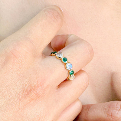 Close-up of a hand wearing a stack of rings with gemstones. Elegant gemstone cabochon ring on model – designer gold jewelry for women by Tresor Collection