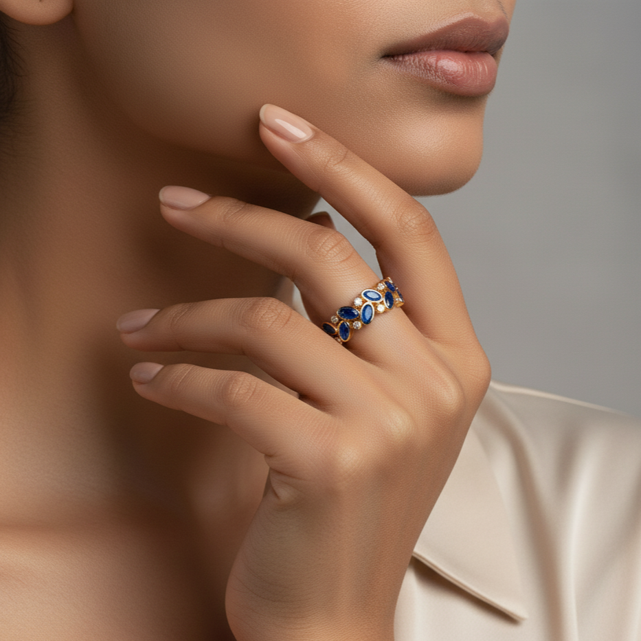Close-up of a hand wearing a decorative ring with a neutral background Elegant blue sapphire gold ring on model – designer gold jewelry for women by Tresor Collection